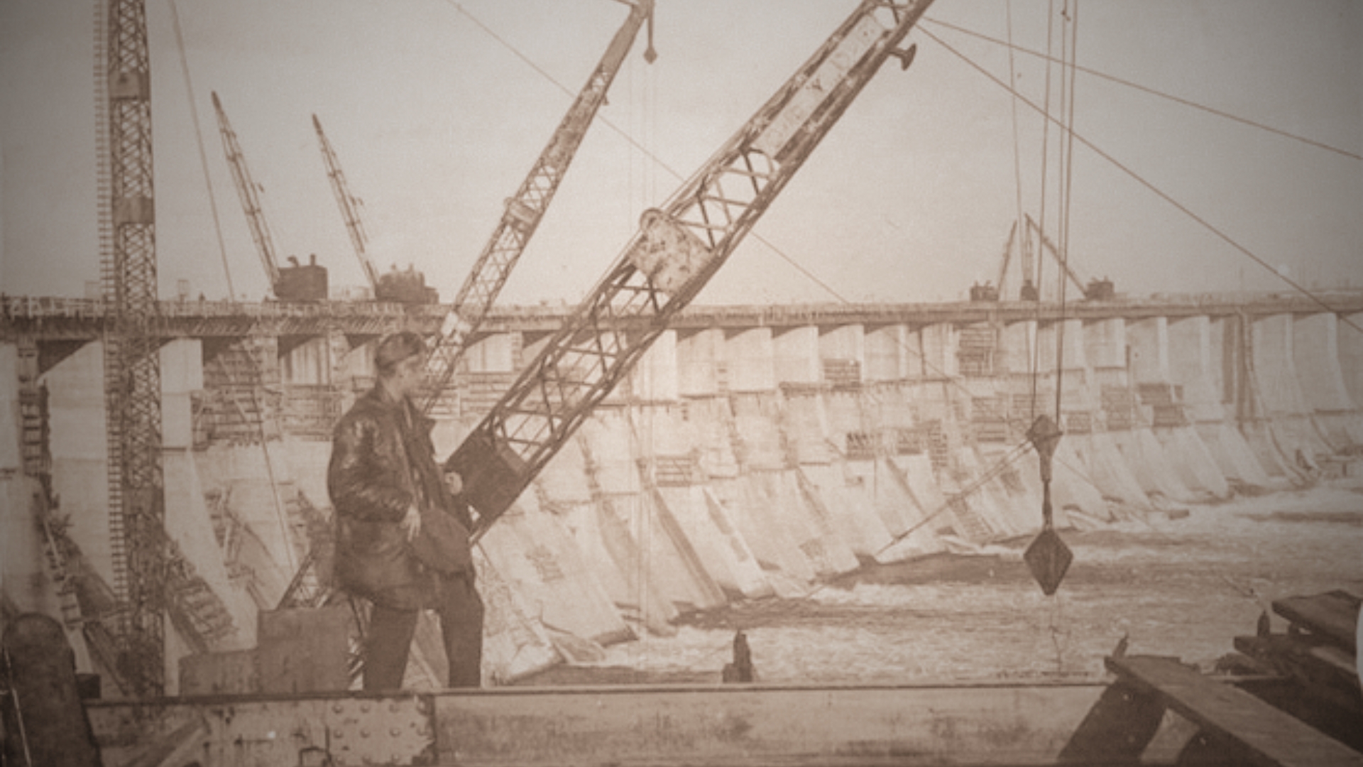 Obras do socialismo em marcha: construção da hidrelétrica de Dniprostroi, na Ucrânia soviética, início da década de 1930.
A monumental barragem sobre o rio Dnieper simboliza o esforço da União Soviética em acelerar a industrialização sob o comando de Stálin. Projetos como este eram apresentados como vitórias do trabalho coletivo e da engenharia socialista. Entre 1931 e 1934, vivendo no exílio na URSS, Luís Carlos Prestes trabalhou em companhias estatais ligadas à construção civil, inserindo-se diretamente nesse contexto de mobilização técnica e ideológica. A experiência marcou sua aproximação definitiva com o modelo soviético de organização política, econômica e revolucionária.